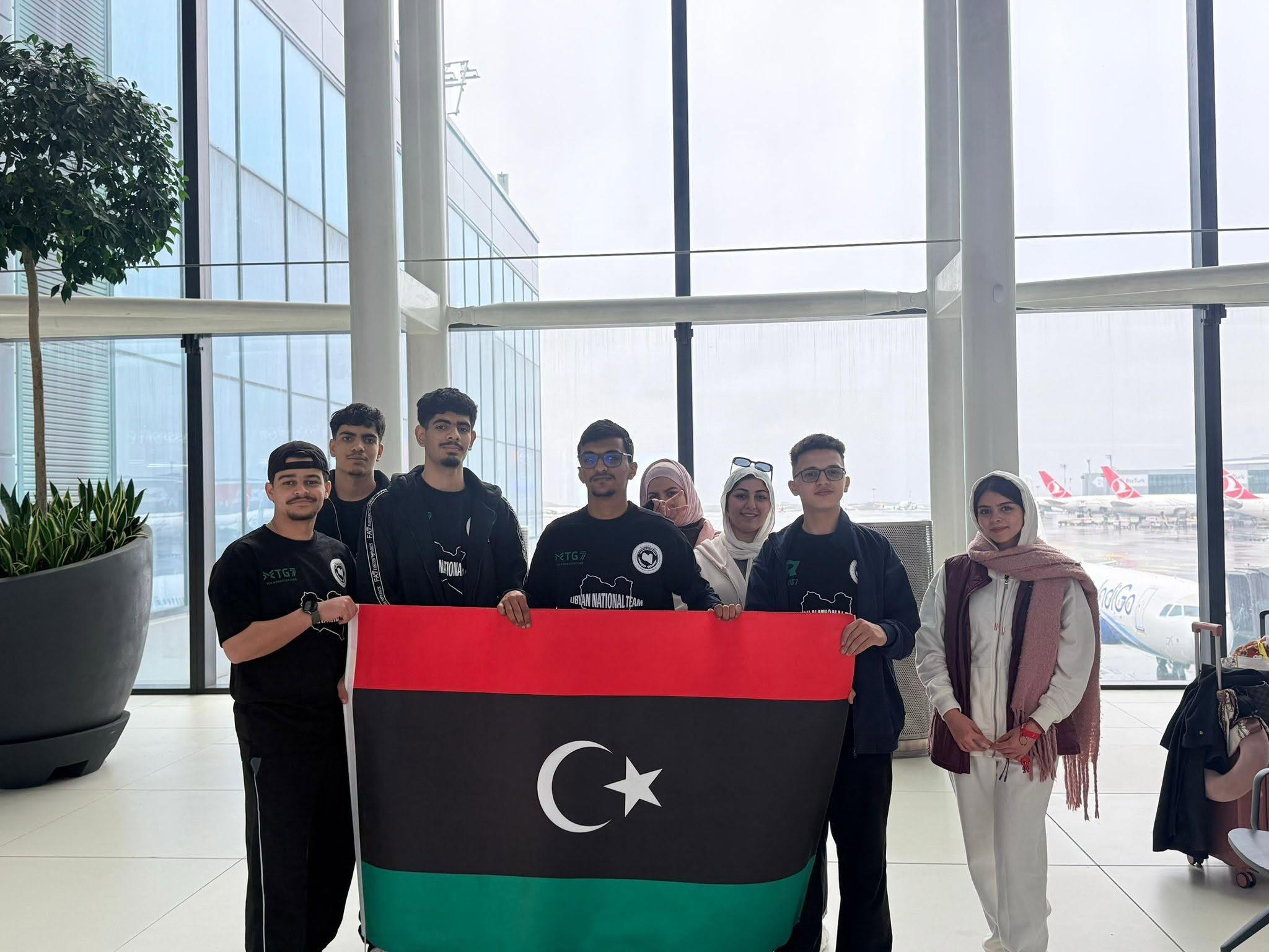 أعضاء من وفدنا، بعضهم بقمصان المنتخب الليبي، يحملون علم ليبيا في صالة مطار بإسطنبول في طريقهم إلى بطولة العالم VEX للروبوتات، مارس 2026